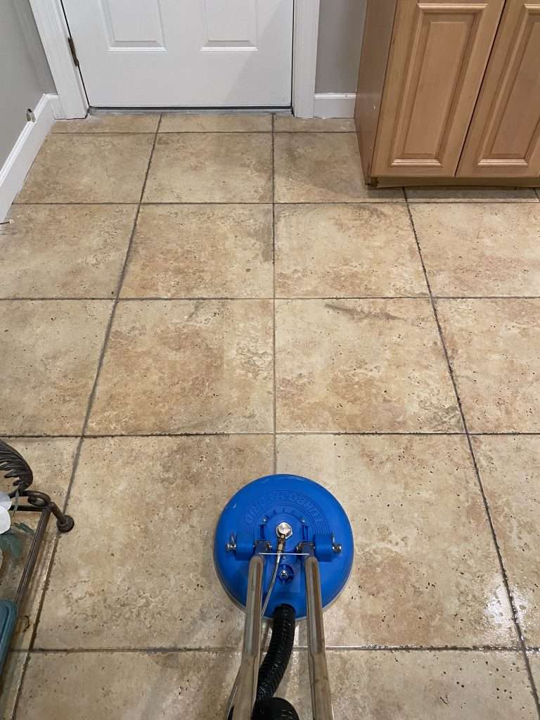Deep cleaning of ceramic tile floor in kitchen, showing professional pressure washing in progress for mold and dirt removal.