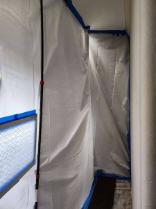 Water damage restoration experts using protective plastic sheeting for containment. Leak containment tarp used during water damage restoration by A+ Integrity Restoration.