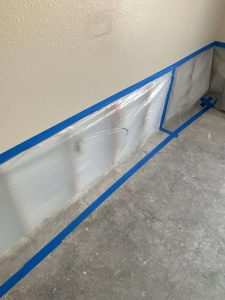 Water damage restoration, drywall repair, and mold prevention services by A+ Integrity Restoration. Aluminum wall moldings with blue painter's tape installed in a residential interior for water damage restoration.