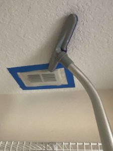 Attic ventilation and HVAC system maintenance for improved air quality and efficiency. Ceiling vent cleaning with a handled vacuum attachment in a home or office setting.