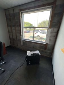 Interior of an office space undergoing water damage restoration, showing air movers and unfinished wall framing, emphasizing professional water damage repair, restoration, and emergency cleanup services by A+ Integrity Restoration. Water damage restoration equipment in an office room with unfinished wall framing, highlighting reliable emergency water damage repair services by A+ Integrity Restoration.
