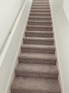 Restored carpeted staircase showcasing expert water and fire damage restoration services provided by A+ Integrity Restoration for home safety and integrity. Professional carpeted staircase restoration with neutral tones, emphasizing reliable fire and water damage repair services by A+ Integrity Restoration.