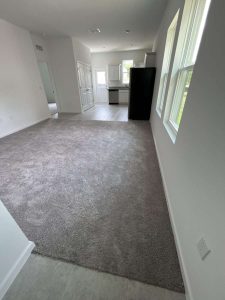 Spacious living area with beige carpet, featuring lots of natural light, ideal for highlighting mold and water damage restoration services provided by A+ Integrity Restoration. Bright, open living room with plush gray carpet and large windows in a modern home, showcasing professional mold removal, water damage restoration, and indoor air quality services by A+ Integrity Restoration.