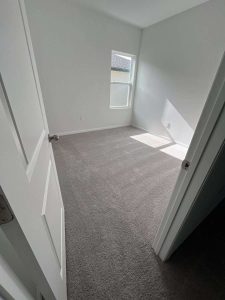 A modern, freshly renovated bedroom featuring neutral paint, plush new carpeting, and improved interior damage repair, exemplifying expert home restoration and mold damage repair services. Bright, clean bedroom with fresh paint and new carpet, ideal for home restoration and repair services, showcasing quality craftsmanship by A+ Integrity Restoration.